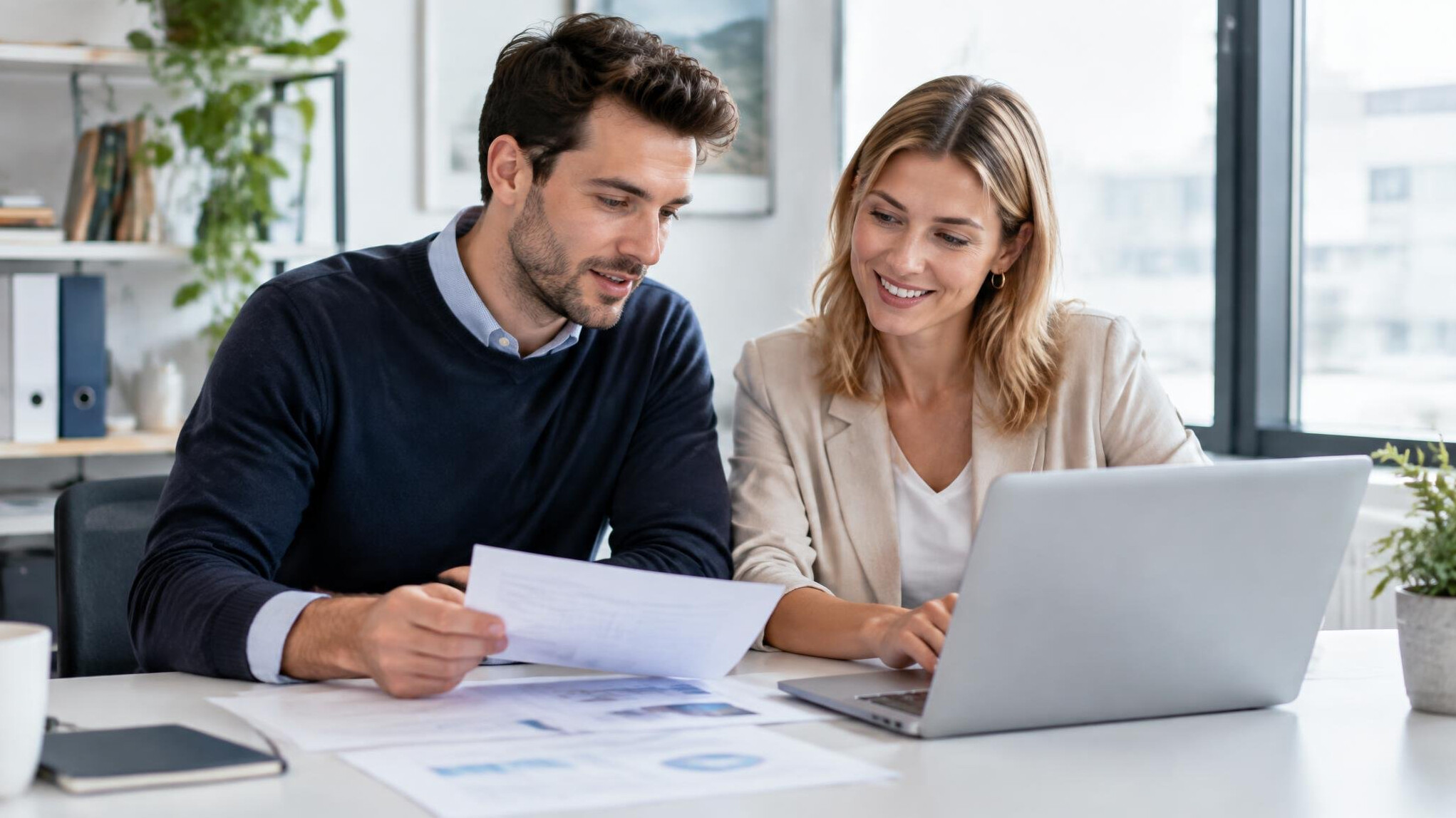 Two coworkers collaborating over documents at a desk